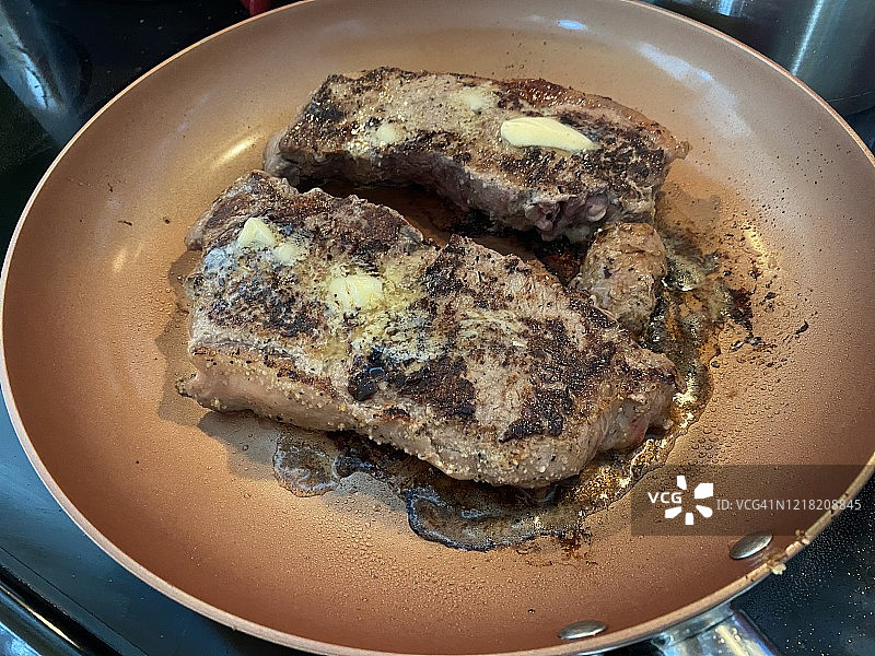 平底锅里煎的两块全熟牛排图片素材