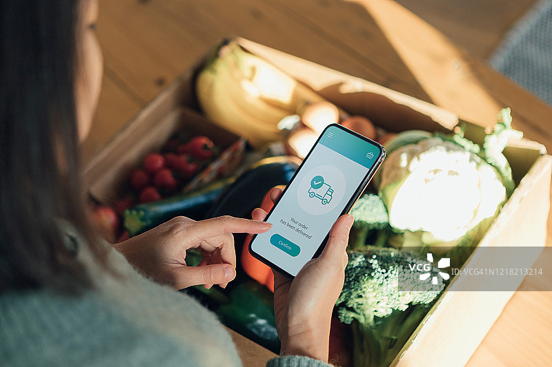 年轻女子用智能手机在线订购食品杂货图片素材