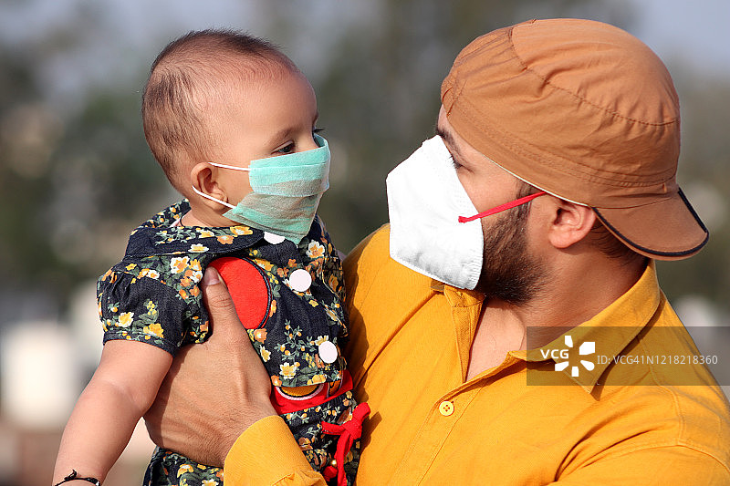 父亲和女婴戴着防雾霾口罩，预防新冠病毒的肖像图片素材