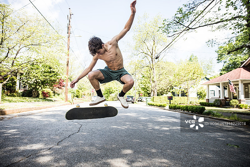 少年在郊区街道上玩滑板图片素材