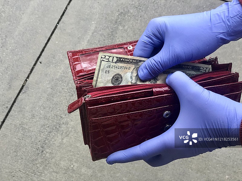 戴手套的手从钱包里拿钱的特写图片素材