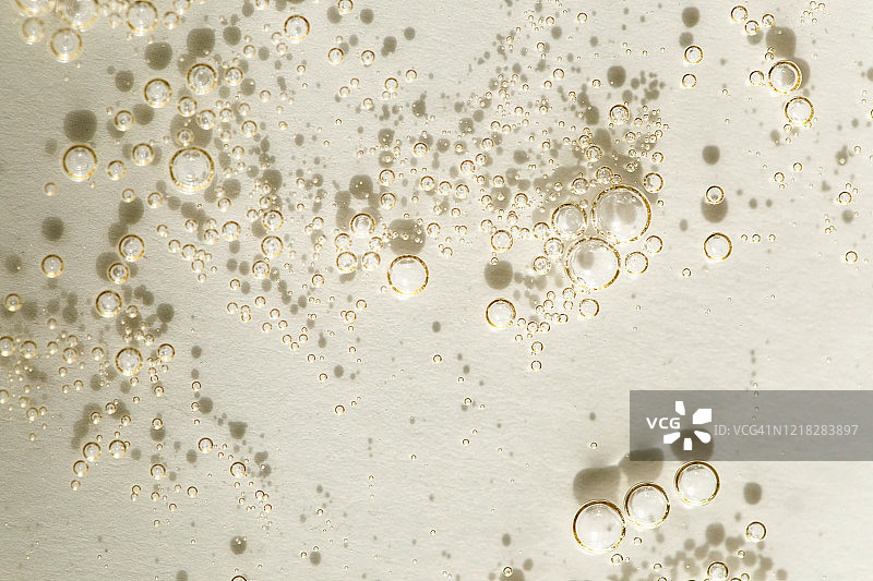 浅黄色背景上的透明气泡啫喱霜。透明质酸液体凝胶（俯视）图片素材