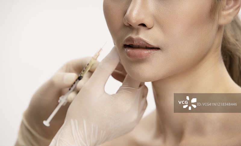 美丽的亚洲女性，皮肤好，戴着手术手套，使用注射器，美容诊所使用肉毒杆菌和面部护理手术概念图片素材