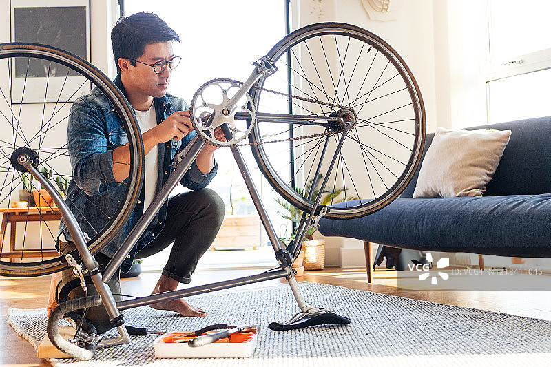 在家修理自行车的专注年轻人图片素材