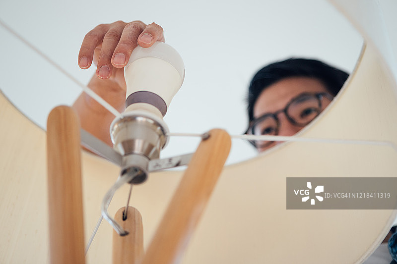 青年男子在家更换灯泡图片素材