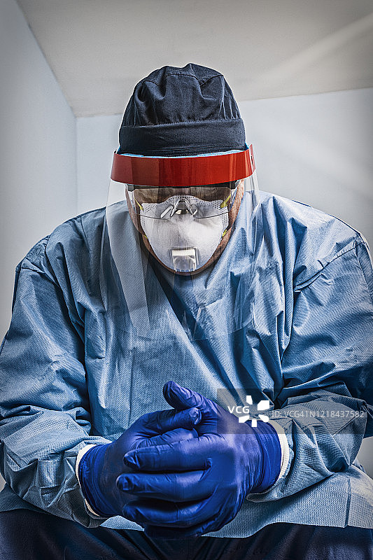 疲惫的医生护士穿防护服低头双手紧握图片素材