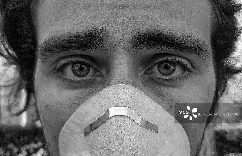 戴着口罩以保护自己免受病毒侵袭的年轻男子面部肖像图片素材