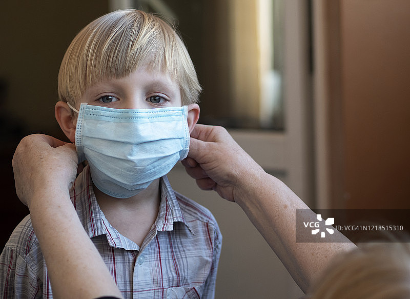 祖母给孙子戴上防护口罩，以保护他免受冠状病毒 COVID-19 侵害图片素材
