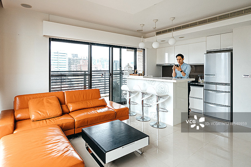 在厨房里使用手机的男人图片素材