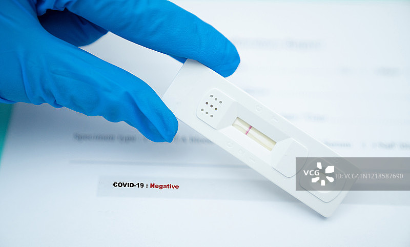 医生手持COVID-19病毒检测试剂盒，新冠病毒快速检测阴性图片素材