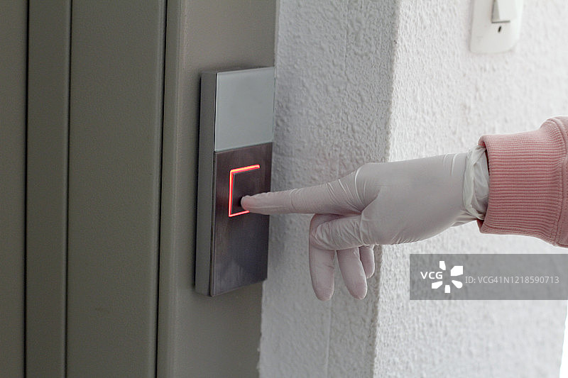 戴着防护手套的手擦拭电梯中的按钮图片素材