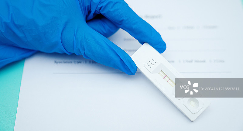 医生手持COVID-19病毒检测试剂盒，新冠病毒快速检测阴性图片素材