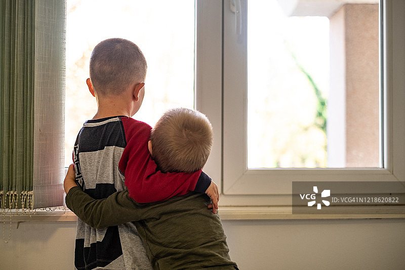 从后方看，男孩们正在看窗外图片素材
