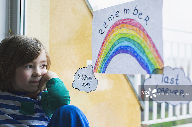 快乐的男孩在家隔离，在窗户上画画，新冠疫情危机图片素材