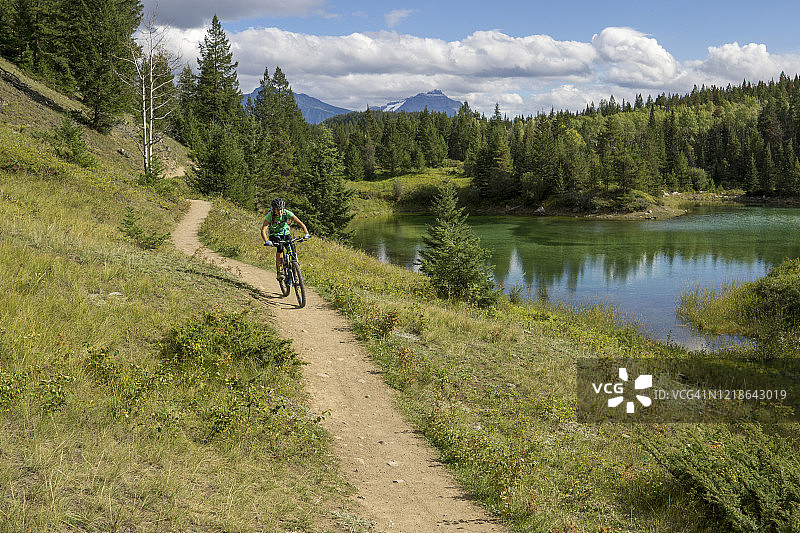 一名女子在湖边风景优美的trail小路上骑山地自行车。图片素材