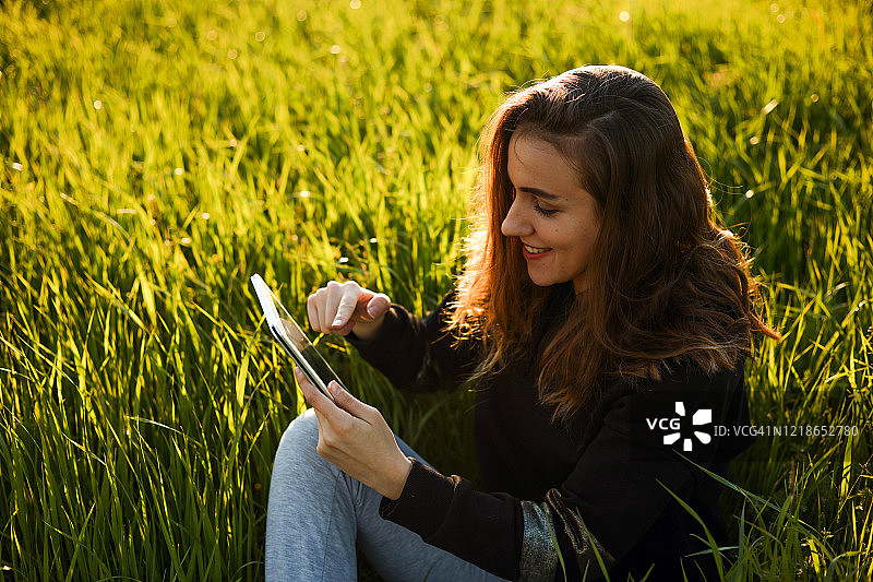 年轻女人触摸平板电脑听音乐、查看电子邮件和视频通话图片素材