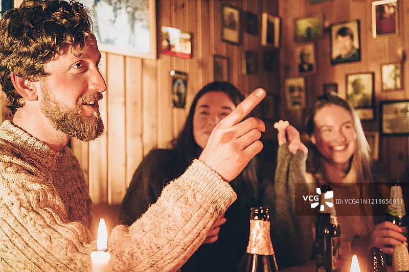 夜晚朋友们在小木屋里享用美食饮品图片素材
