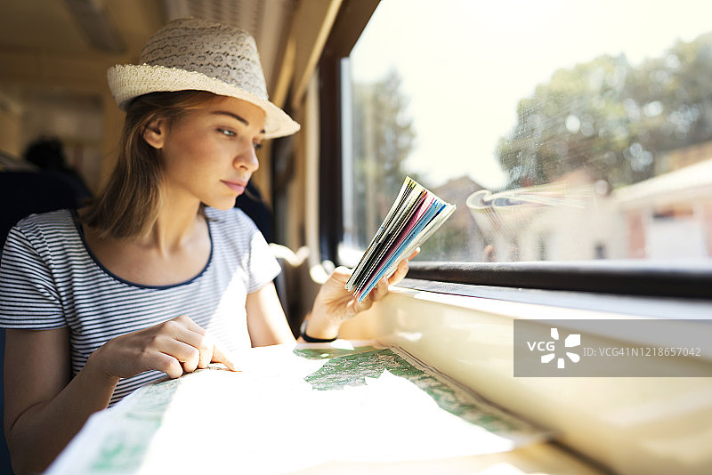 在火车上阅读指南的年轻漂亮白人女子图片素材