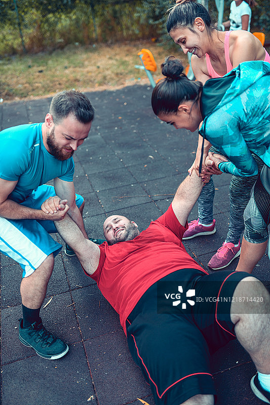 朋友们帮助疲惫超重的朋友在训练后起身图片素材