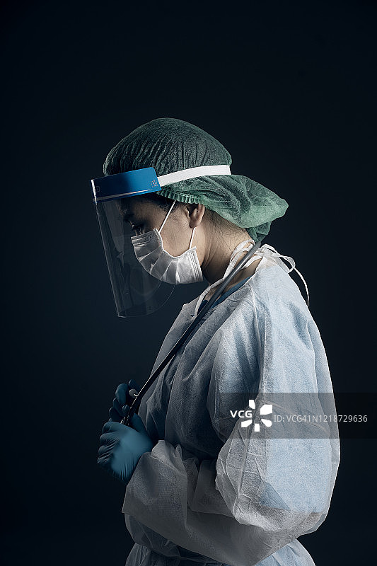 疫情期间身穿PPE防护服的医生感到压力并在祈祷图片素材