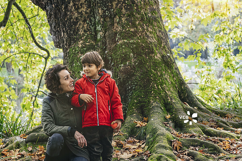 年轻的母亲和她可爱的小儿子在公园里散步。图片素材