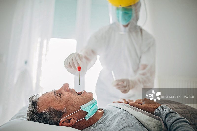医生在家中为老年男性进行咽拭子检测，以进行新冠病毒检测图片素材