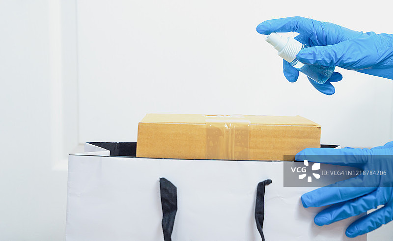 送货上门，配送员用消毒酒精擦拭购物袋表面图片素材