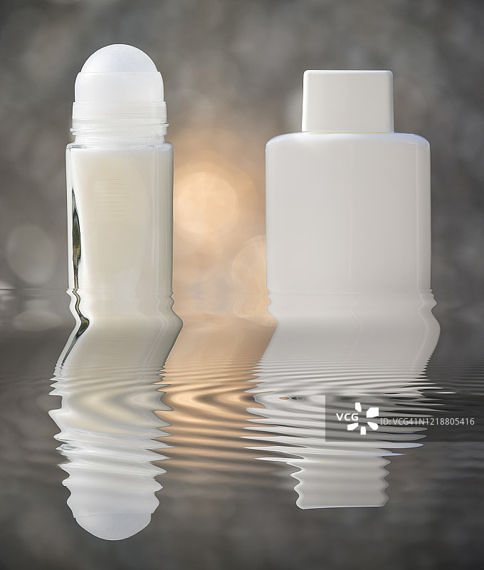 阳光照射的水面上的除臭剂和须后润肤露容器图片素材