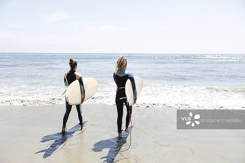 海滩上穿着潜水服准备冲浪的两位女士图片素材