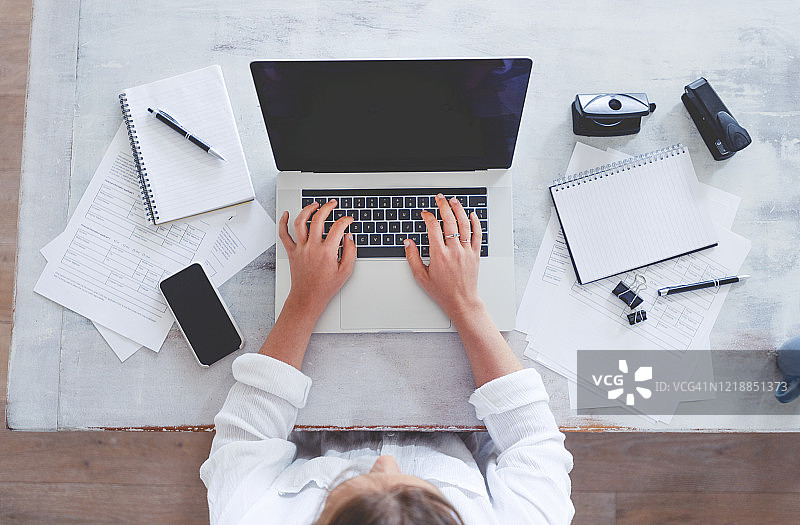 俯视角度：女子在桌旁使用笔记本电脑图片素材