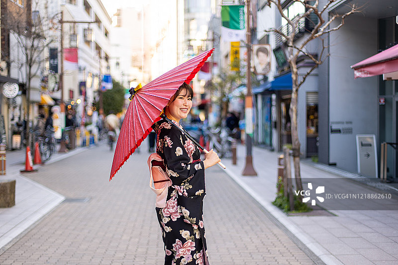 穿着和服的快乐年轻女子走在购物街上图片素材