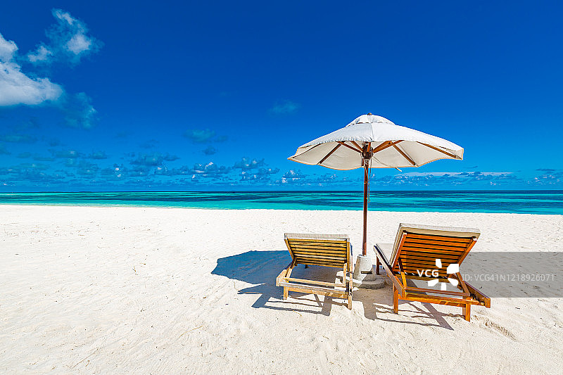 热带海滩夏季景观，配有躺椅、棕榈树和平静的海面，适合海滩banner。奢华的旅行景观，是度假或旅游的绝佳目的地。海滩风光图片素材