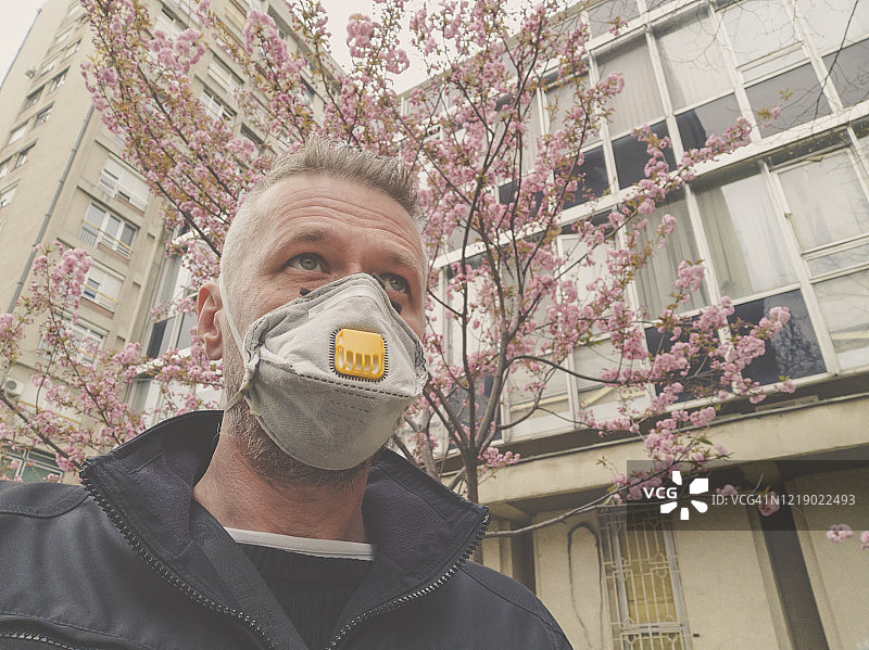 男人在城市户外戴着防护口罩，防止病毒感染图片素材