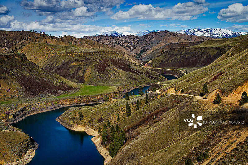 道路沿着博伊西河南叉的壮观峡谷边缘延伸，远处是内华达州西南部积雪的圣三一山图片素材