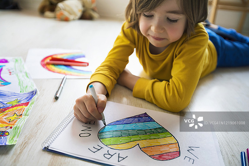 快乐的男孩在家画爱心，希望概念，新冠疫情图片素材