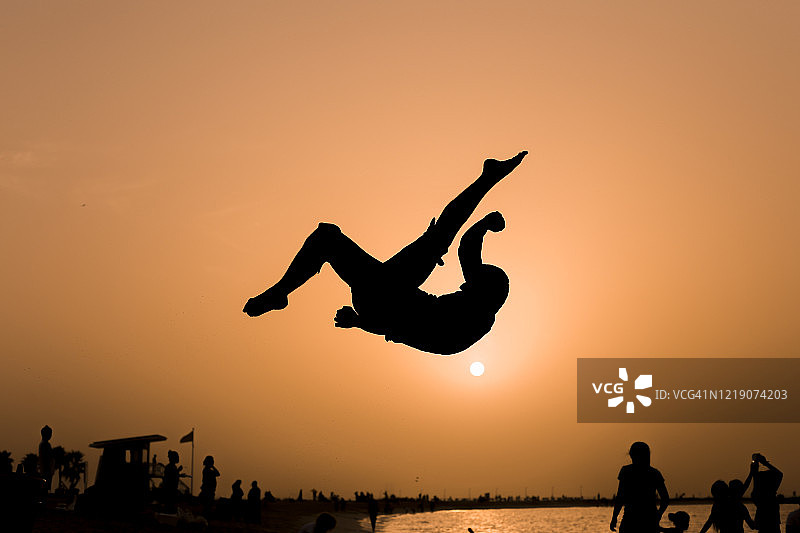 日落时分的后空翻跳跃剪影图片素材