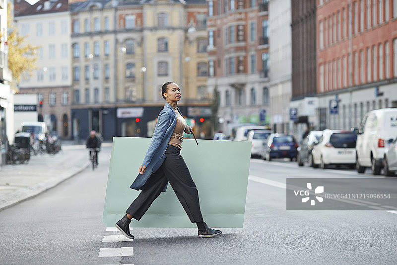 女人拿着大购物袋在城市街道上行走图片素材