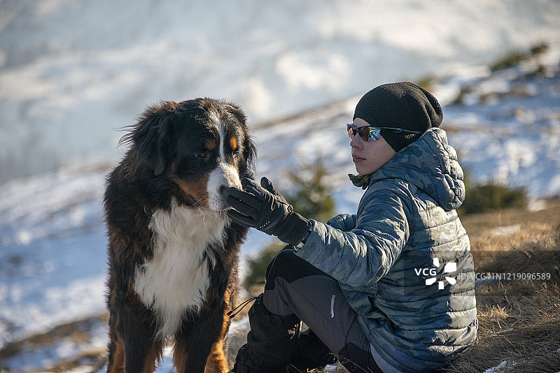 冬天户外拥抱伯恩山犬的孤独男孩图片素材