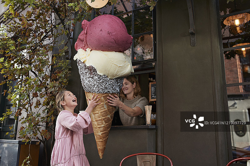 女孩从咖啡馆外卖柜台购买大冰淇淋甜筒图片素材