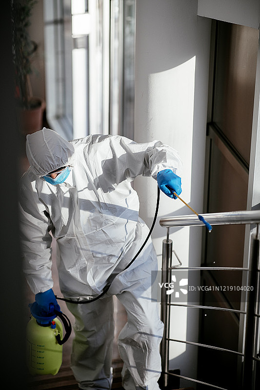 穿着防护服消毒建筑物台阶的男人库存照片图片素材
