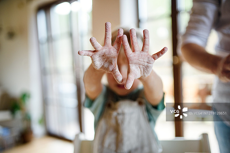 小男孩在家做披萨，展示沾满面粉的双手图片素材