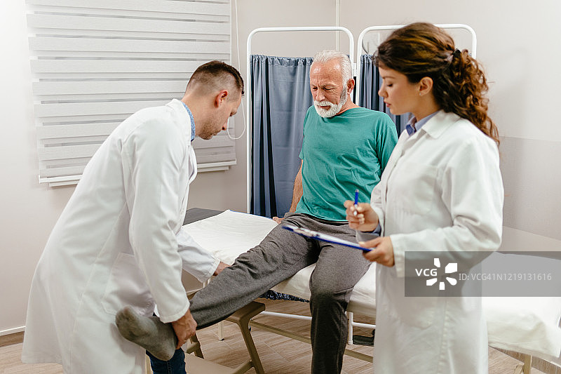 医生检查老年男性患者的腿部损伤图片素材