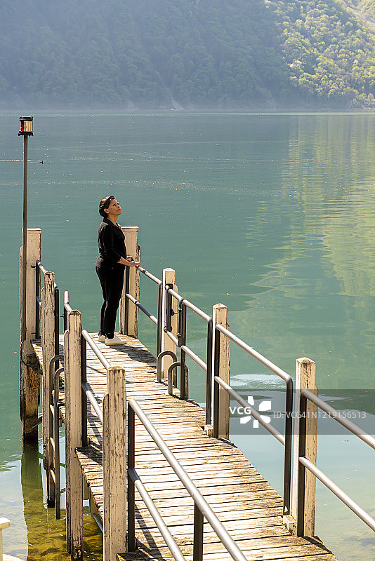 站在码头和高山湖泊旁的女人图片素材