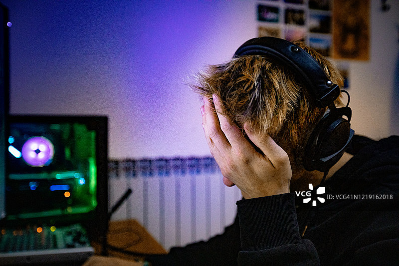 因输掉电子游戏而捂脸的男孩（库存照片）图片素材