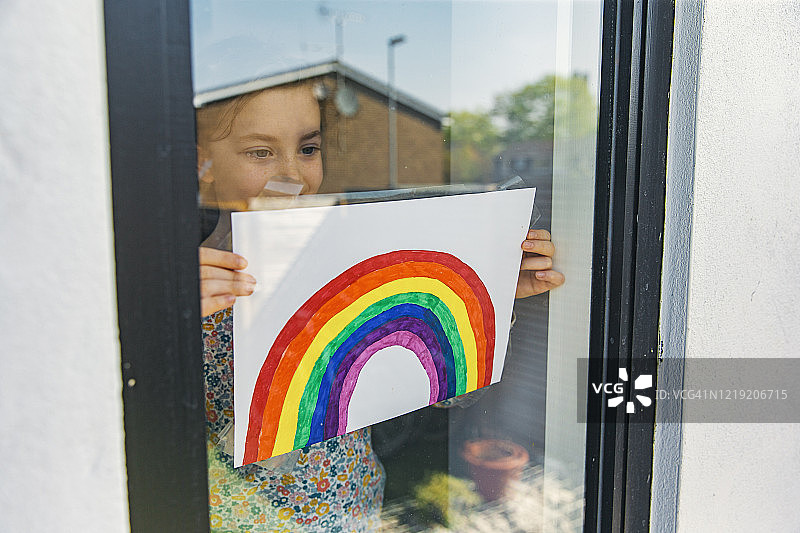 小女孩把彩虹画放在窗户上图片素材