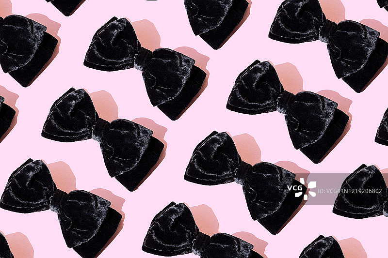 粉色背景上的重复黑色领结图片素材