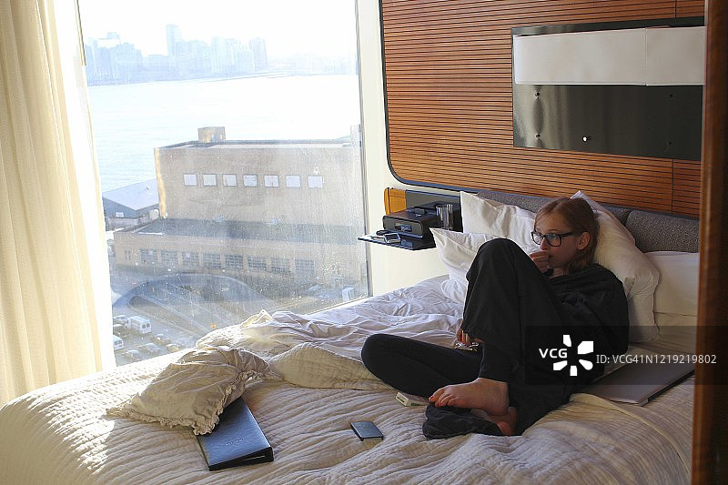 靠在床上的红发小女孩，戴着黑色眼镜，穿着黑色浴袍图片素材