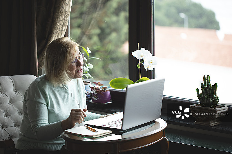 独自使用笔记本电脑进行视频聊天的老年妇女图片素材