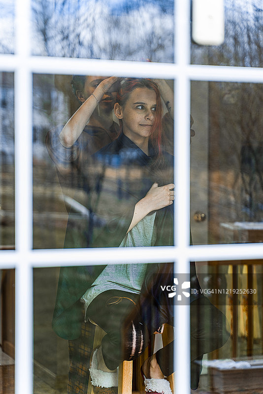 从后门廊透过玻璃门看客厅里姐姐给妹妹剪头发图片素材