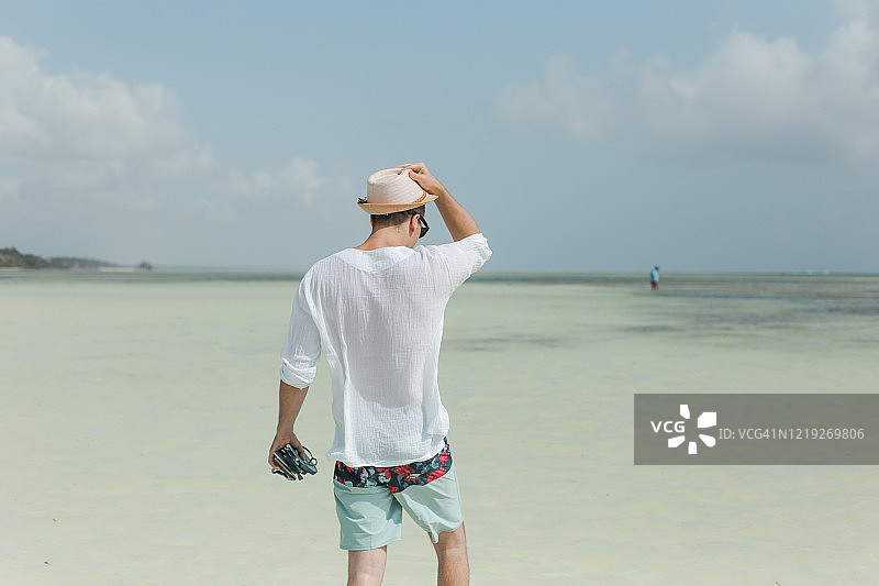 戴夏日帽子的年轻男人在美丽热带海滩上图片素材